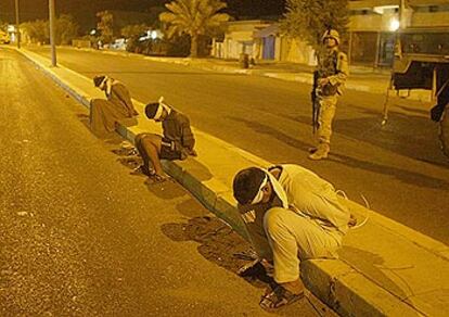 Un soldado estadounidense vigila a varios detenidos durante una redada en la madrugada de ayer, en Tikrit.