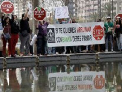Un grupo de activistas de la plataforma Stop Desahucios protesta a las afueras del Palacio de Congresos de Valencia.