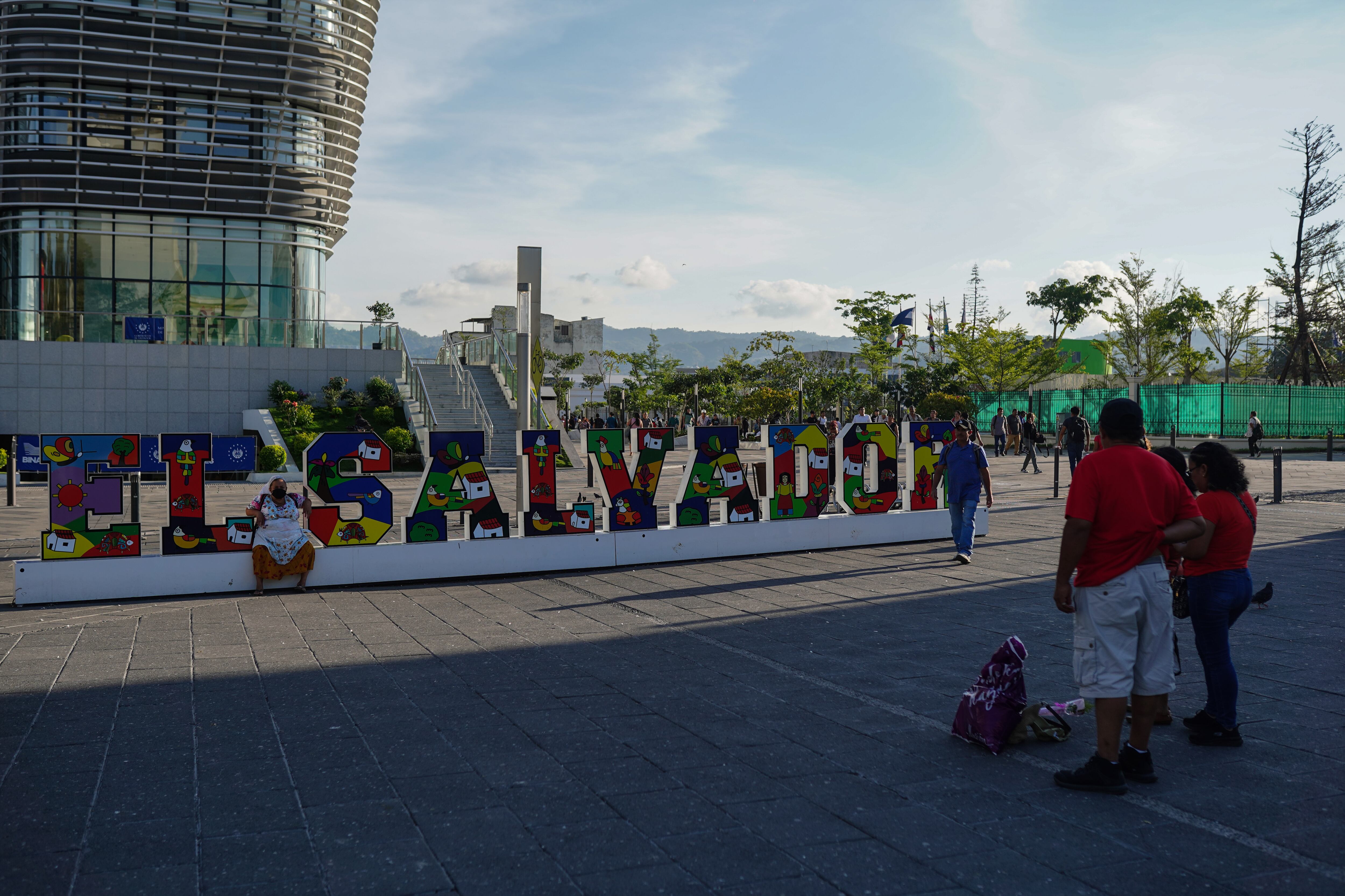 Una mujer se toma un retrato junto a un letrero que lee 'El Salvador' en San Salvador, el 7 de marzo de 2025.