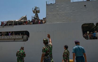 Un soldado saluda a los tripulantes de un barco de la navía en el que son evacuados de Palu.