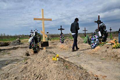 Un hombre pasea cerca de la tumba de Mykhaylo Romaniuk (a la derecha de la imagen), en el cementerio de Bucha, el pasado 25 de abril. Romaniuk acompañaba aquel día a Oleksandr Smagliuk, de 21 años y novio de su sobrina, al hospital militar de la vecina ciudad de Irpin. Los dos hombres esperaban localizar al padre del joven, que había resultado gravemente herido por un bombardeo y estaba desaparecido. También pensaron que allí encontrarían electricidad para cargar sus teléfonos y pedir ayuda. 