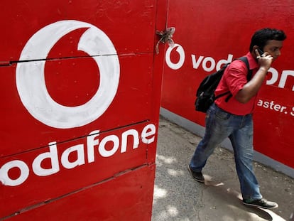 Un hombre habla por el m&oacute;vil al lado de los carteles de Vodafone