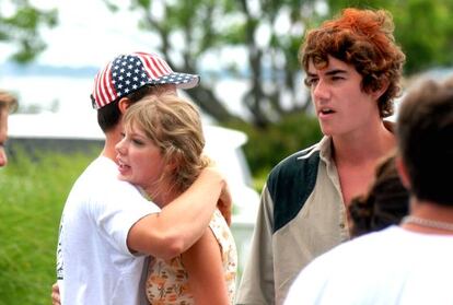 Taylor Swift abraza a un joven bajo la atenta mirada de su novio Conor Kennedy.