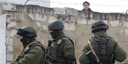 Un hombre ucranio observa a unos uniformados en la base militar de Perevalnoye (Crimea), este jueves.