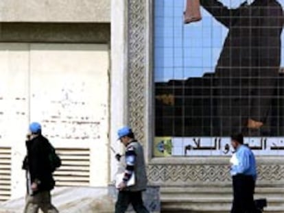 Varios inspectores pasan junto a un retrato gigante de Sadam Husein.