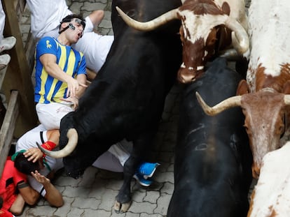 Varios mozos caen mientras son perseguidos por toros de Victoriano del Río, en el tercer encierro de los Sanfermines.