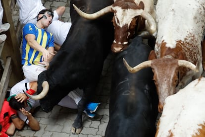 Un grupo de mozos caen al suelo al paso de los astados de la ganadería de Victoriano del Río, este martes en San Fermín. 