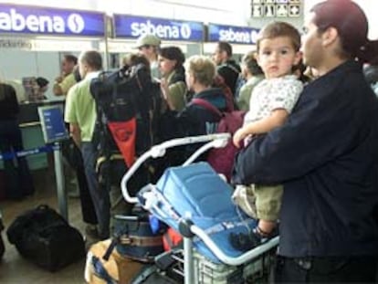 Un padre sujeta a su hijo en una cola frente al mostrador de Sabena en el aeropuerto de Zavent en Bruselas