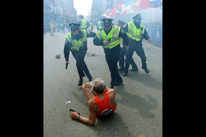 La policía de Boston, arma en mano, inspecciona el lugar de la explosión momentos después de se produjera en la zona de la meta del maratón.