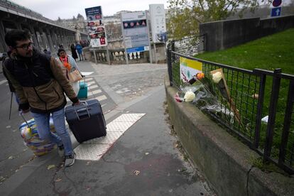 Un hombre camina el domingo 3 de diciembre junto a las flores colocadas en la escena donde un hombre atacó a los transeúntes la noche anterior.