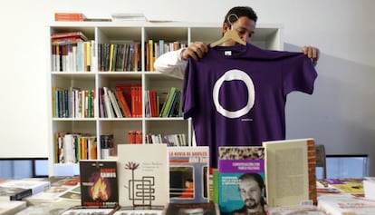 Un simpatizante de Podemos muestra una camiseta con su logo en un local del partido en Madrid.