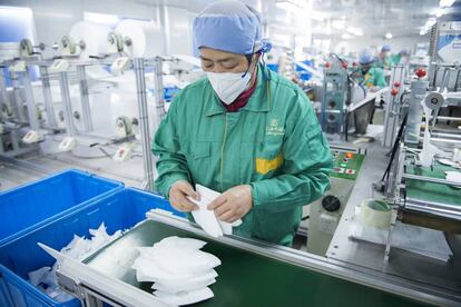Un empleado de Dasheng revisa las mascarillas recién fabricadas.
