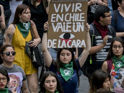 Manifestante segura cartaz onde se lê: “Viver no Chile custa o olho da cara”.