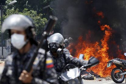 Policías se alejan de las llamas tras una explosión en la Plaza Altamira de Caracas.