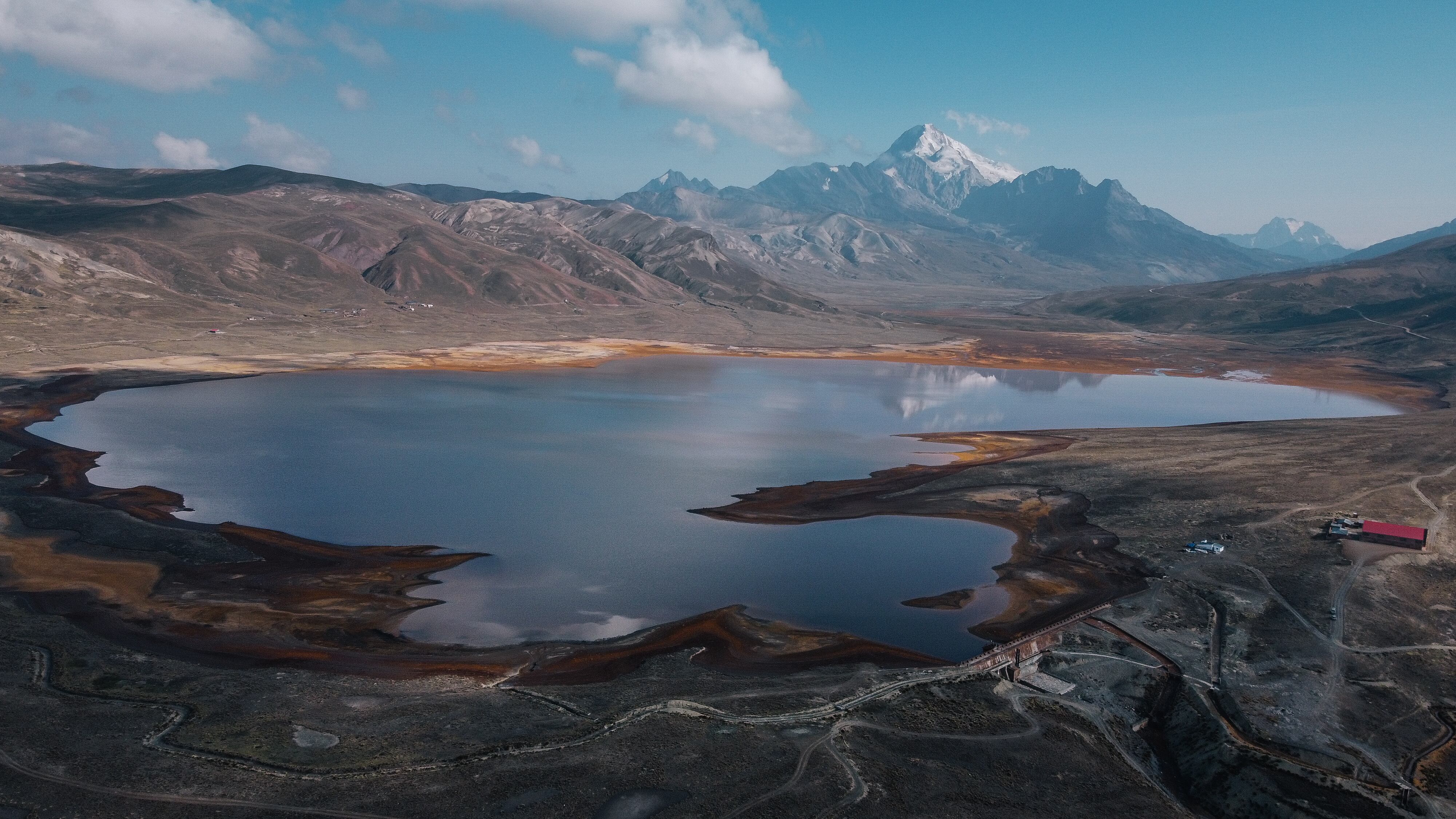 La montaña Huayna Potosí, al fondo de la represa de Milluni, ha experimentado en los últimos años un retroceso del hielo. En la ladera derecha se observa un campamento minero sin actividad, en el momento de la toma de esta fotografía, el pasado 21 de noviembre.