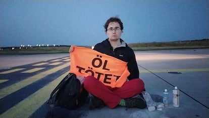 Imagen difundida por Letzte Generation que muestra a un activista este jueves en el aeropuerto de Fráncfort con un cartel en el que se lee: "el petróleo mata".