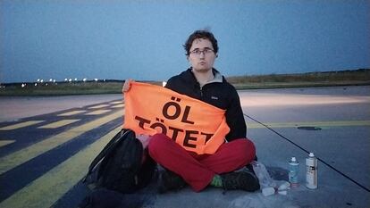 Imagen difundida por Letzte Generation que muestra a un activista este jueves en el aeropuerto de Fráncfort con un cartel en el que se lee: "el petróleo mata".