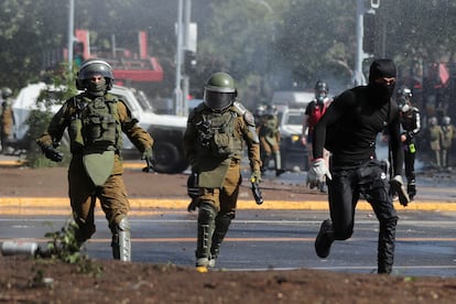 Un manifestante huye de dos policías durante una manifestación por el tercer aniversario del estallido social, este martes en Santiago de Chile.