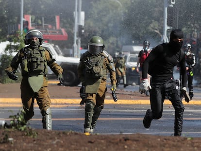 Un manifestante huye de dos policías durante una manifestación por el tercer aniversario del estallido social, este martes en Santiago de Chile.