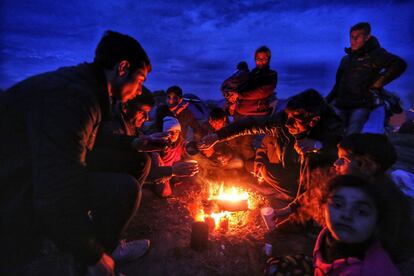 Un grupo de migrantes comparten un té junto a un fuego en Idomeni.