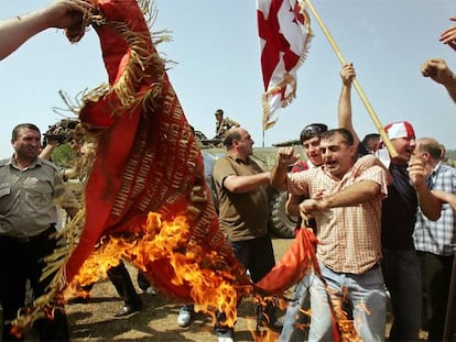 Un grupo de georgianos quema una bandera de la época soviética frente a soldados rusos en la localidad de Chorotchku.