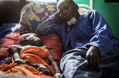 Un niño aquejado de una forma grave de meningitis en la unidad de pediatría con su abuelo.