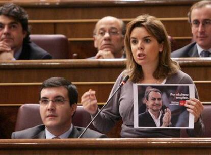 La portavoz del PP, Soraya Sáenz de Santamaría, muestra uno de los lemas electorales del PSOE para las últimas elecciones.