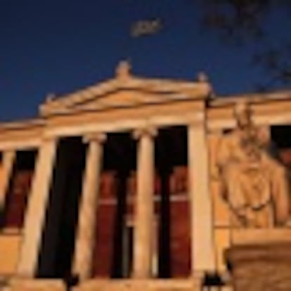 A Greek national flag flutters on top of the Athens' University during sunset in Athens