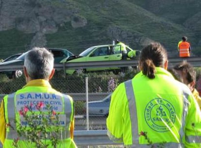 Personal de los servicios de emergencias junto a los coches tras el accidente.