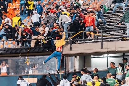 Un hincha del Junior de Barranquilla cuelga de uno de los balcones del estadio, durante los enfrentamientos con los hinchas del Atlético Nacional, en Medellín, el 26 de septiembre de 2024.