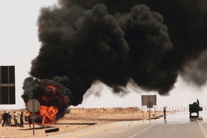 Un vehículo conducido por soldados de Gadafi arde tras ser atacado por los rebeldes, a 138 kilómetros de Sirte.