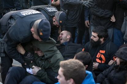 Agentes de la Brigada Mobil de los Mossos d'Esquadra desalojan a activistas que cortaban el tráfico en la plaza Cerdà de Barcelona por la huelga general.