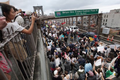 Un grupo de personas fotografía y anima a los manifestantes de Ocupa Wall Street, el sábado en el puente de Brooklyn.