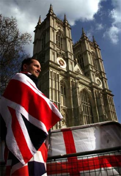 Un ciudadano británico se envuelve en la bandera Union Jack ante la abadía de Westminster.