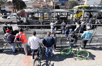 Ciudadanos observan hoy los restos incinerados de buses de TransMilenio en la localidad de Bosa, en Bogotá (Colombia). 