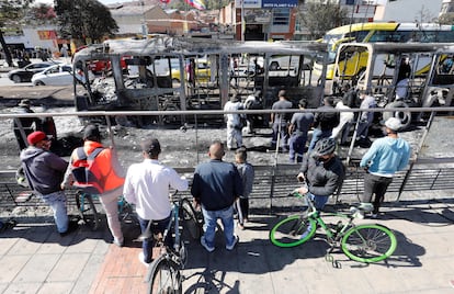 Ciudadanos observan hoy los restos incinerados de buses de TransMilenio en la localidad de Bosa, en Bogotá (Colombia). 