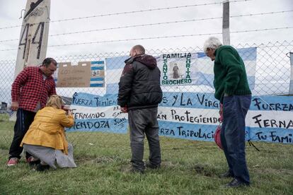 Juan Carlos Mendoza (d) y Carlos Mendoza (i), padre y hermano del submarinista desaparecido Ariel Fernando Mendoza cuelgan una bandera argentina frente a la Base Naval de Mar de Plata, el 20 de noviembre de 2017.