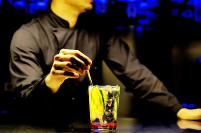 A barman mixes a gin and tonic.