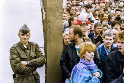 Un soldado alemán del Este observa, cruzado de brazos, la multitud que se reunió para asistir a la apertura del Muro en la calle de Bernauer, en el Este de Berlín, el 14 de noviembre.