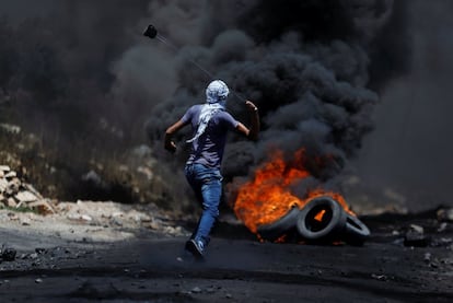 Un manifestante palestino devuelve una bomba de gas lacrimógeno disparada por las tropas israelíes durante los enfrentamientos tras una protesta contra el cercano asentamiento judío de Qadomem, en Cisjordania.