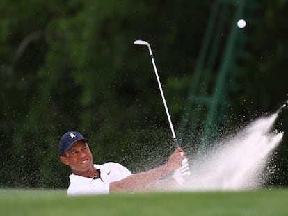 Tiger Woods plays out from a bunker on the 18th hole during the first round of the Augusta National.