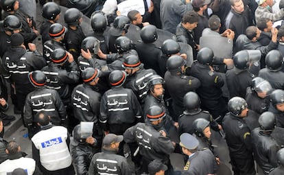 Policías en formación permanece frente a manifestantes para contarles el paso durante la manifestación contra el partido de Ben Ali.