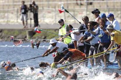 Los equipos suministran agua a los nadadores durante la prueba.