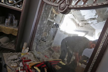 Un hombre sirio, reflejado en un espejo, reúne sus pertenencias en su casa dañada tras un bombardeo en la zona rebelde de Ghouta, en Damasco (Siria)