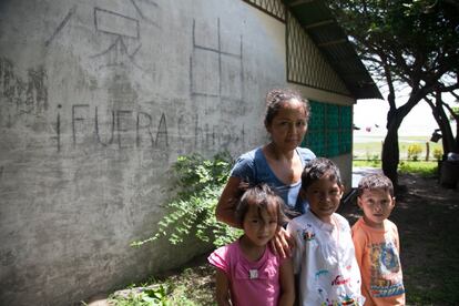 Julia Espinoza posa con sus hijos delante de su casa en Obrajuelo, a la orilla del lago. A pesar de las amenazas mantiene el "Fuera chinos" pintado en la fachada.