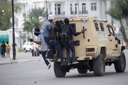 Manifestantes viajan en la parte trasera de un vehículo blindado de la Policía Nacional de Haití durante el tiroteo.