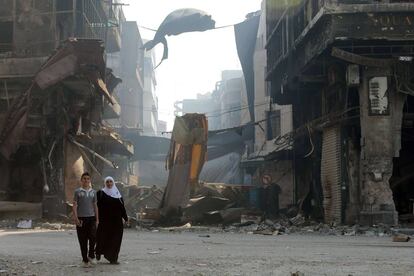 Ciudadanos sirios caminan entre las ruinas de las calles de Homs días después de que los rebeldes abandonasen la ciudad.