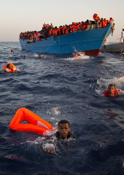 Uno de los migrantes se acerca a un bote salvavidas después de saltar de una patera.