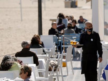 Un camarero atiende las mesas de una terraza de un bar en la playa de la Malvarrosa, en Valencia.