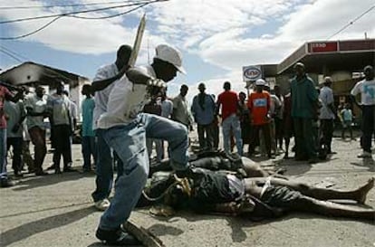 Dos jóvenes haitianos patean y apalean los cuerpos de dos polícías muertos a tiros, ayer en Gonaives.